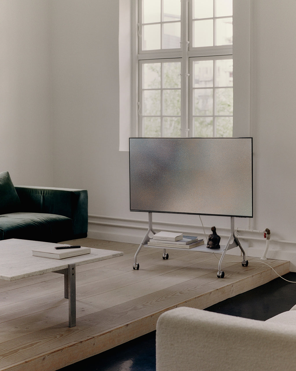 Moon in Cloudy Silver rolling TV stand with wheels holding a flatscreen in a bright minimalist living room